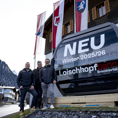 Die neue 10er Gondel der Loischkopfbahn steht vor dem Gemeindezentrum Bürserberg. Die Bürgermeister der Dörfer Brand und Bürserberg und der Geschäftsführer der Bergbahnen Brandnertal stehen vor der Gondel. | © Bergbahnen Brandnertal, Viviane Seils