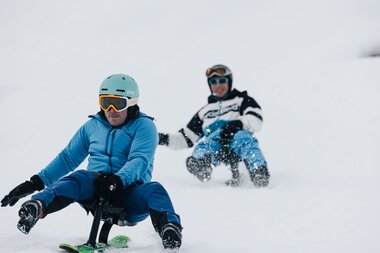 Ein sportliches Rennen auf dem Snooc | © Bergbahnen Brandnertal, Timo Hummel Ein Rodler im Vordergrund rodelt konzentriert auf dem Snooc während ihn ein anderer Rodler verfolgt. | © Bergbahnen Brandnertal, Timo Hummel
